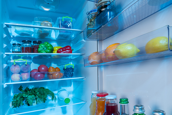 Open interior of a fridge packed with fresh vegetables.