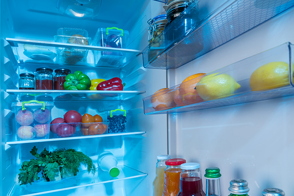 Open interior of a fridge packed with fresh vegetables.