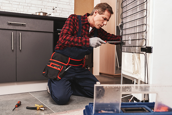 Fridge repairman working on a fridge.