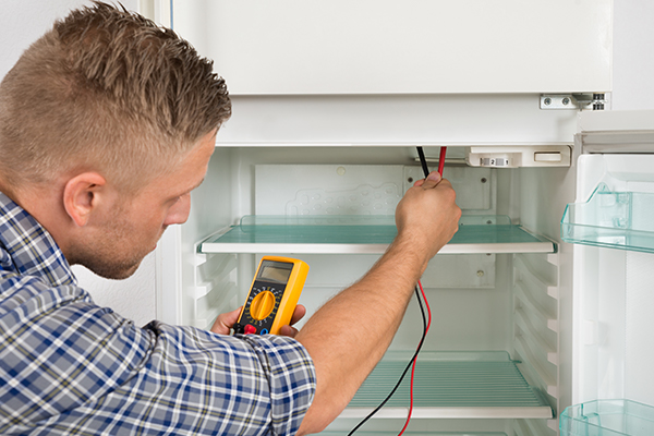 Repair man working on the inside of the fridge.