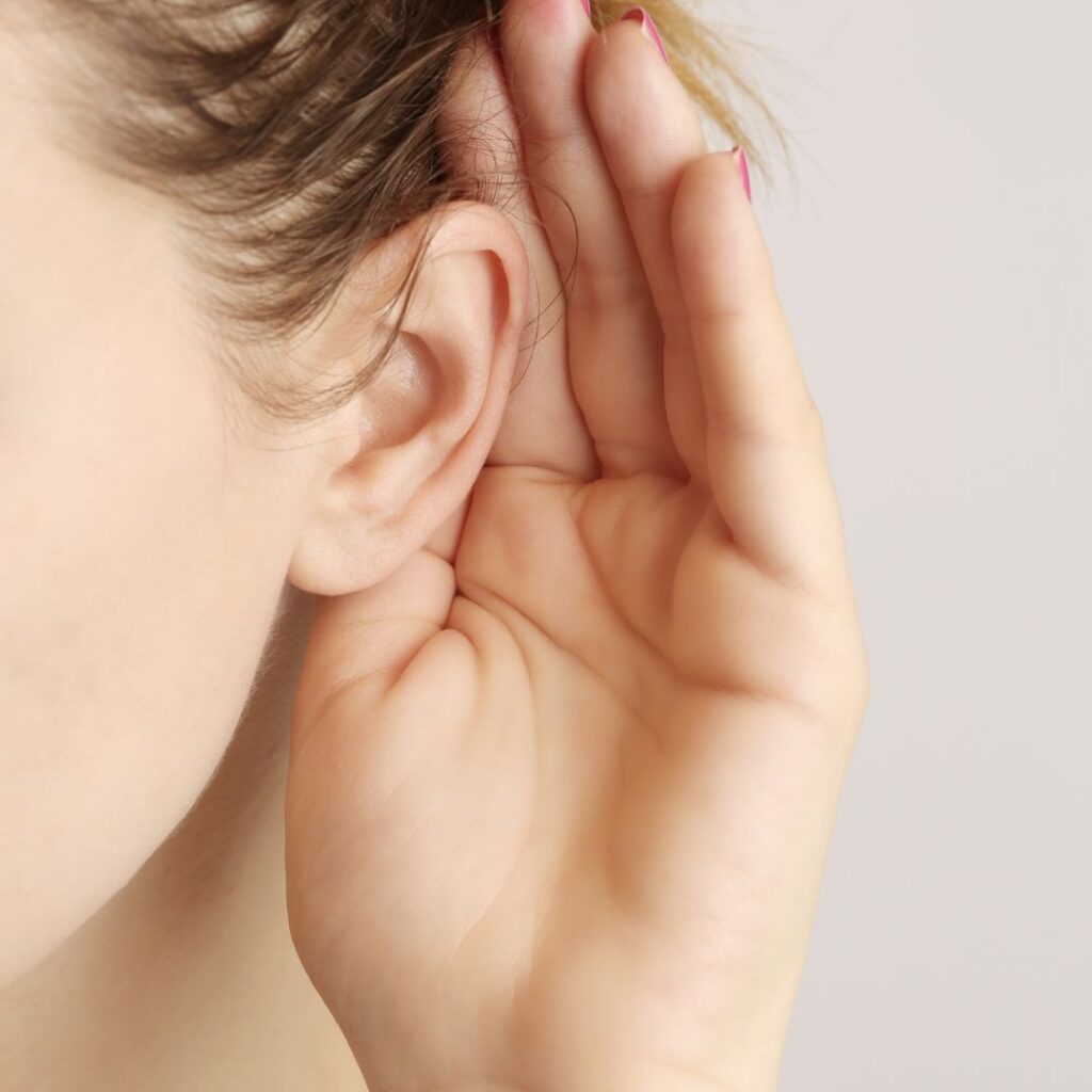 Person holding up their hand next to their ear to listen