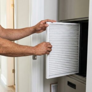 A technician replacing a clean air filter in a residential furnace system.