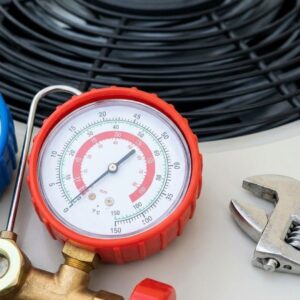 A pressure gauge attached to a commercial air conditioning unit shows an issue, with a service wrench nearby.