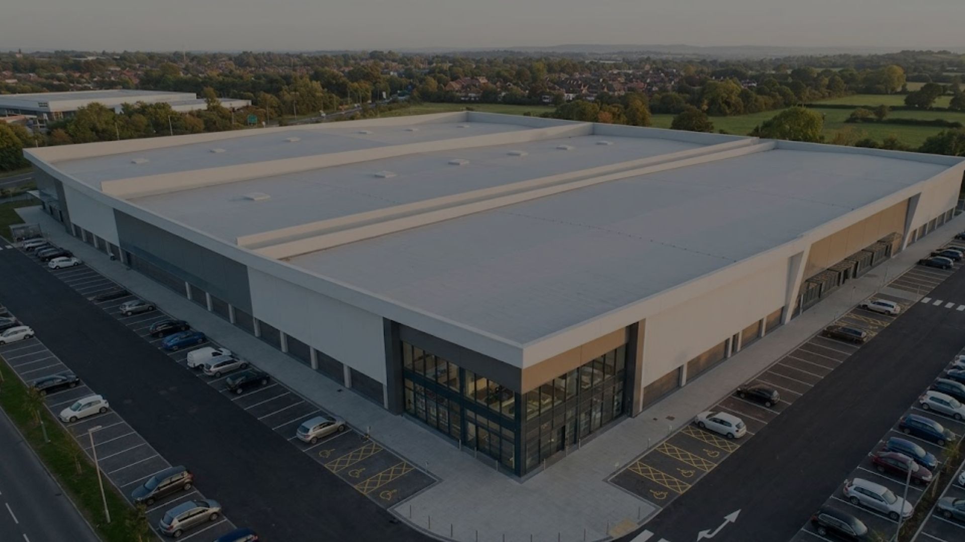 A modern retail building features a large, clean, light grey rooftop under soft daylight.