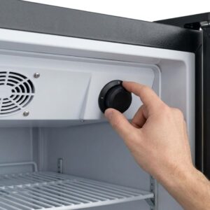 A hand reaches in to adjust the internal temperature dial of a professional reach-in cooler.